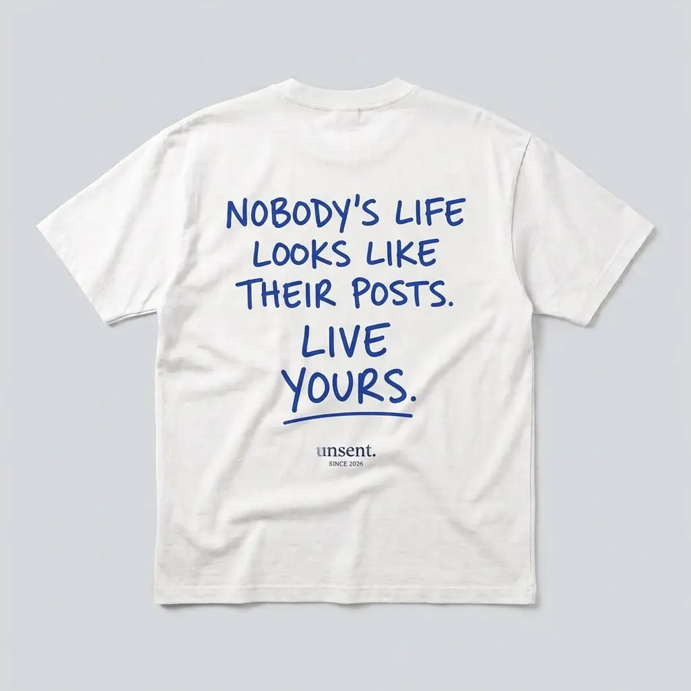 White tee, royal blue print on the back: Nobody’s life looks like their posts. Live yours.